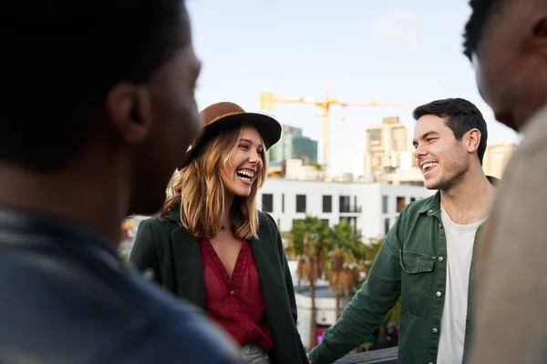 Mujer caucásica riendo con grupo de amigos multiculturales socializando en una terraza en la azotea al atardecer. — Foto de Stock