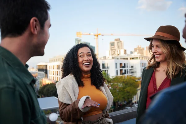 Biracial femelle riant avec groupe d'amis multiculturels socialisant sur un toit-terrasse au crépuscule. — Photo