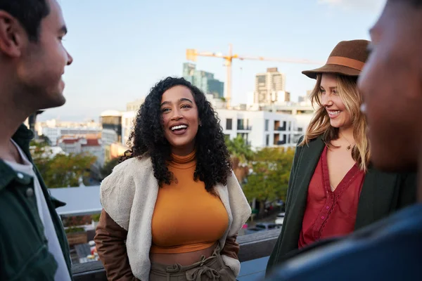 Біреальні жінки спілкуються з групою багатокультурних друзів, спілкуючись на терасі на даху в сутінках . — стокове фото