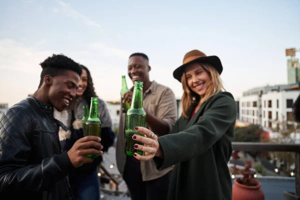 Grupo de jóvenes adultos multiculturales haciendo un brindis con bebidas en una terraza en la azotea de la ciudad. — Foto de Stock
