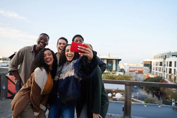 Grupo multicultural de amigos tomando una selfie en una fiesta en la azotea. Atractivos amigos adultos jóvenes, posando para la cámara. — Foto de Stock