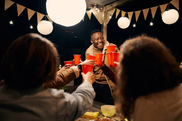 Czarny mężczyzna stoi, wiwatuje z grupą różnorodnych przyjaciół świętujących na przyjęciu na świeżym powietrzu. Dobre czasy i śmiech — Zdjęcie stockowe