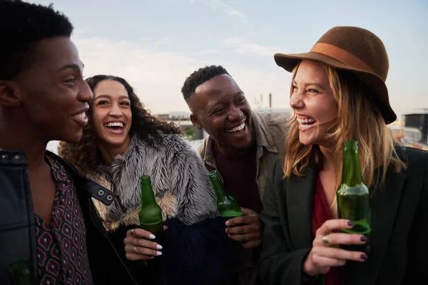 Lachende Gruppe multikultureller junger Erwachsener, die sich auf einer Dachterrasse in der Stadt treffen. Drinks in der Hand, lächelt mit Freunden. — Stockfoto