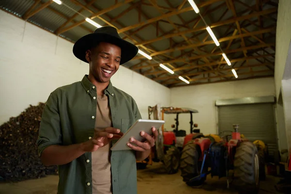 Mixte race mâle agriculteur tapant sur tablette numérique debout dans hangar — Photo