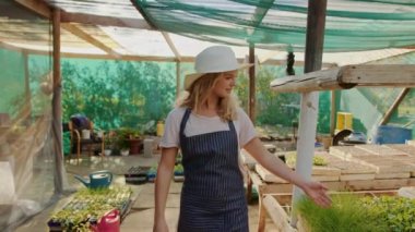 Beyaz kadın çiftçi yeşil evde kolları bağlı yürüyor. 