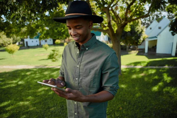 Змішана раса чоловічого фермера, що друкує на цифровому планшеті, що стоїть на відкритому повітрі — стокове фото