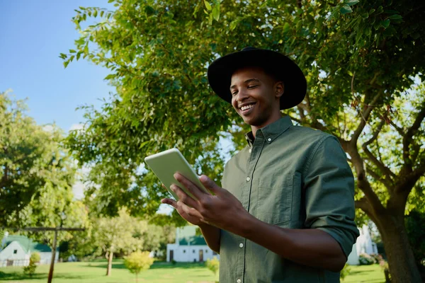 Змішана раса чоловіків-фермерів, що стоять на відкритому повітрі, друкуючи на цифровому планшеті — стокове фото