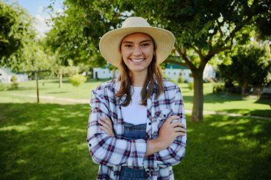Beyaz kadın çiftçi dışarıda kolları bağlı duruyor.