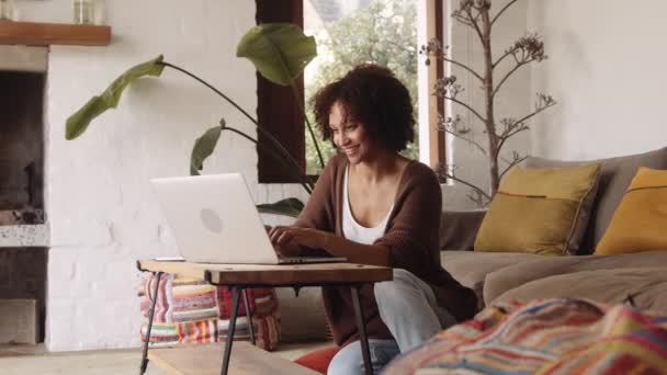 Biracial kvinna arbetar hemifrån på sin bärbara dator i modern stil vardagsrum på dagtid — Stockvideo