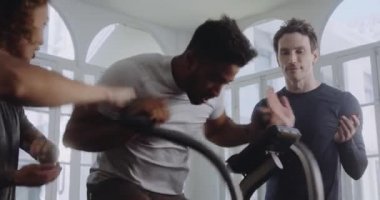 Modern stil bir spor salonunda çift ırklı erkek çok çalışıyor. Arkadaşları onu motive ediyor ve destekliyor..