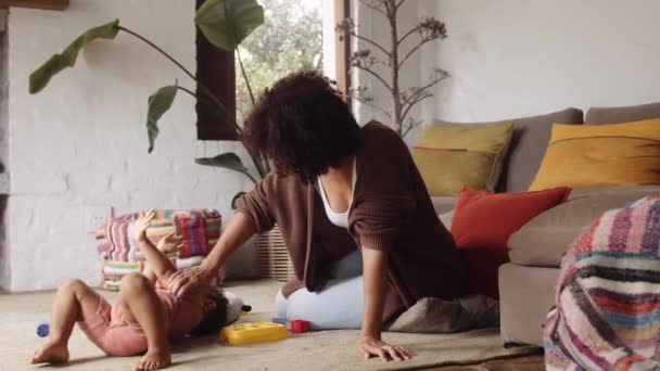 Mujer Biracial cosquillas a su hijo pequeño en la sala de estar de estilo moderno durante el día. Jugando con juguetes. — Vídeos de Stock