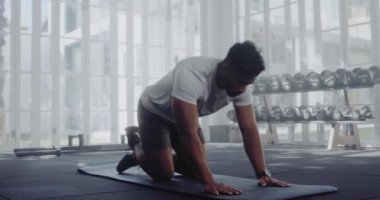 Modern tarz spor salonundaki çift ırklı erkek saatine zamanlayıcı takıyor ve şınav çekiyor..