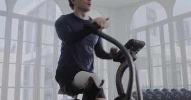Havada bisiklet süren protez bacaklı, kararlı, beyaz bir erkek. Modern tarzda spor yapan engelli bir sporcu..