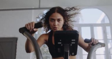 Modern tarz spor salonunda çift ırklı bir kadın hava bisikleti üzerinde çok çalışıyor. Fitness ve sağlıklı yaşam tarzı.