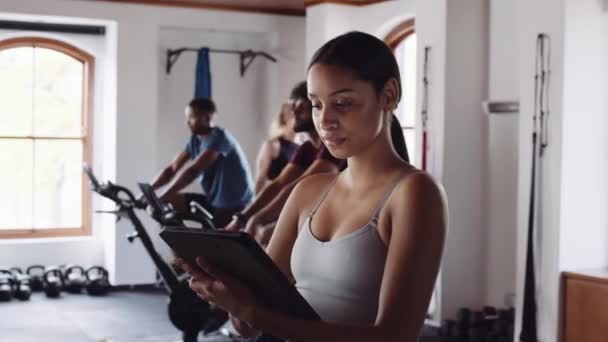 Concentrato giovane adulto proprietario di palestra femminile biennale utilizzando la tecnologia per eseguire palestra interna di fitness durante il giorno. — Video Stock