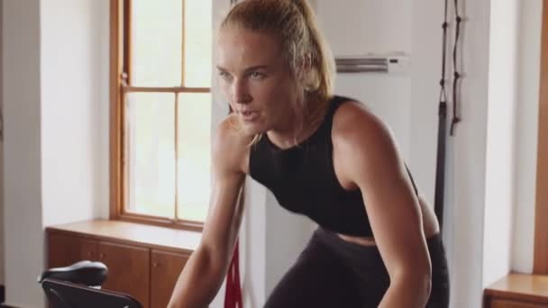 Deterimed a silný mladý běloška žena cyklistika na tělocvičně v krytém fitness tělocvičně — Stock video