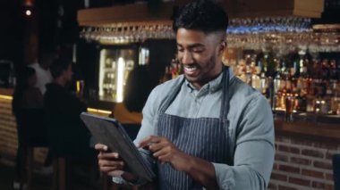 Lokantada çalışan bir adam tablete bakıp gülümsüyor..