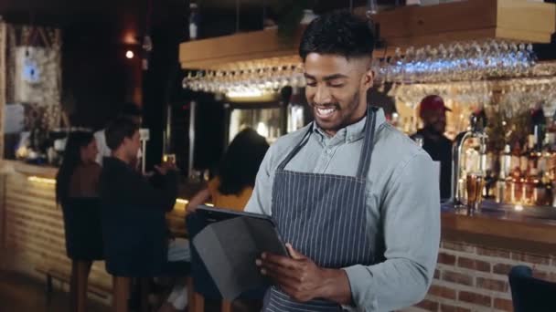 Человек, который работает в ресторане, смотрит на планшет и улыбается — стоковое видео