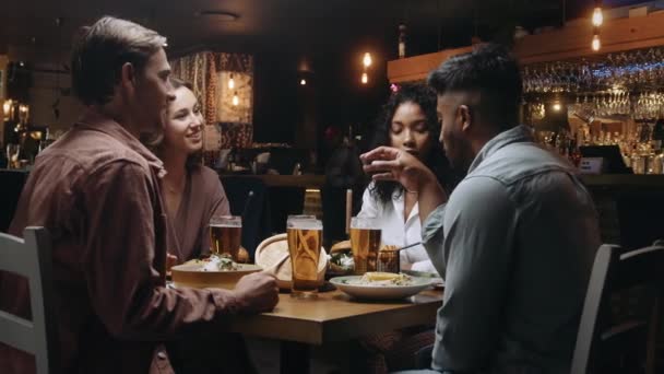 Eine Gruppe multiethnischer Freunde unterhält sich bei Abendessen und Bier in einem Restaurant — Stockvideo