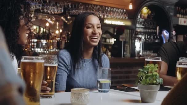 Eine multiethnische Gruppe von Freunden trinkt Bier in einem Restaurant, lacht und führt angenehme Gespräche. — Stockvideo