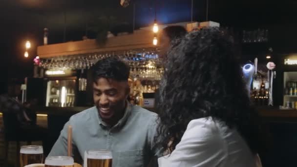 Cameriera porta multi-etnico gruppo di amici al ristorante il loro cibo. Poi battono i loro bicchieri di birra. — Video Stock