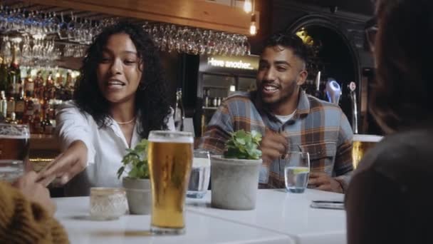 Eine multiethnische Gruppe von Freunden, die in einem Restaurant Bier trinken, lachen und sich amüsieren. — Stockvideo