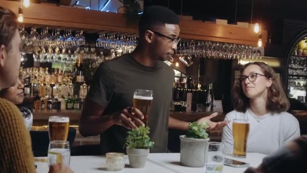 Homme multiracial au restaurant avec un groupe d'amis. Il porte un toast et tout le monde prend ses lunettes. — Video