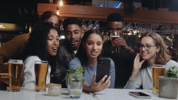 Μια ομάδα πολυεθνικών φίλων σε ένα εστιατόριο σε βιντεοκλήση με έναν από τους άλλους φίλους τους. — Αρχείο Βίντεο