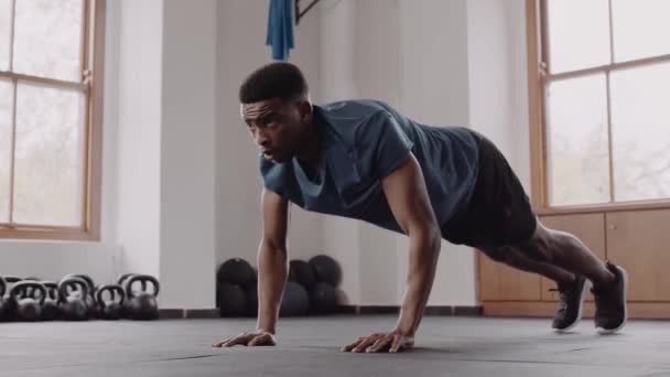 Cocok dan sehat hitam laki-laki di sebuah gym kebugaran dalam ruangan. Terfokus, dan mempersiapkan diri untuk latihan push up. — Stok Video