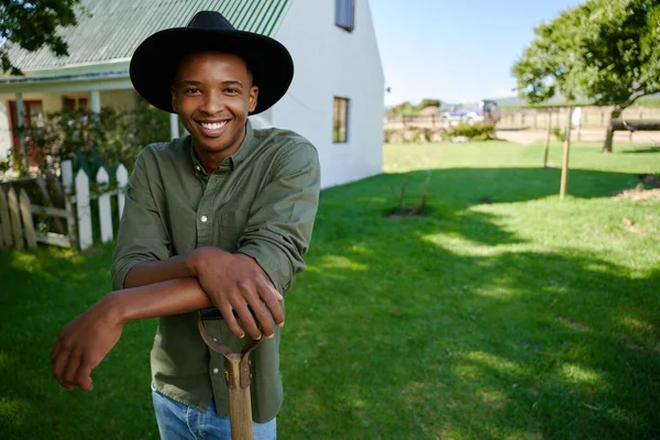 Mixed race male farmer standing in green field leaning on pitch fork — 스톡 사진