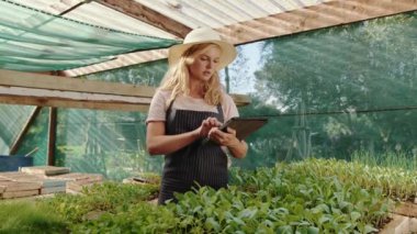 Caucasian female farmer working in green house holding digital tablet