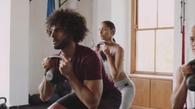 Spor salonunda grup fitness sınıfında kettlebell tutan kararlı yetişkinler grubu.. 