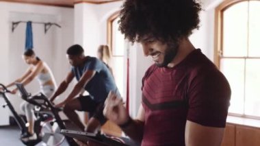 Neşeli Ortadoğulu genç yetişkin erkek, spor salonunda spor yaparken tablet ve kalem kullanan fitness uzmanı..