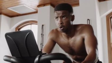 Formda ve sağlıklı siyah erkek spor salonunda spor bisikleti sürüyor. Yüksek kalite 4k görüntü