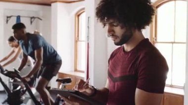 Spor salonundaki spor salonunda tablet ve kalem kullanan orta doğulu genç bir erkek.. 