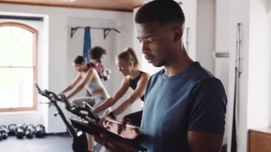 Kendine güvenen genç zenci erkek kapalı spor salonunda tablet kullanıyor. Sağlıklı yaşam tarzını destekleyen fitness profesyoneli. 