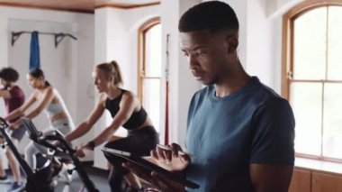 Genç siyahi erkek, spor salonunda elektronik tablet kullanıyor. Güvenilir fitness profesyonel rehberlik sağlar. 