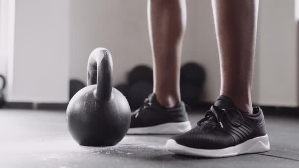 近距离的黑人男性用他手上的粉末从地上抓起水壶铃 室内健身馆的运动 — 图库视频影像