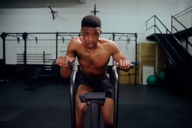 Çapraz antrenman sırasında eliptik antrenör kullanan Afrikalı Amerikalı bir erkek. Erkek kişisel antrenör spor salonunda yoğun bir şekilde egzersiz yapıyor. Yüksek kalite fotoğraf