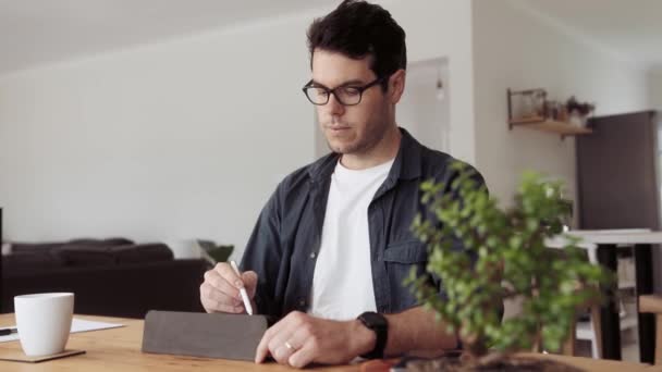 Biały Mężczyzna Rysujący Tablecie Elektronicznym Piórem Siedząc Przy Stole Jadalni — Wideo stockowe
