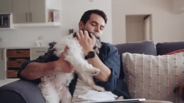 Caucasian man playing with pet dog while sitting on couch at home. High quality 4k footage