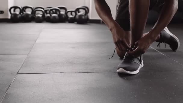 健康健康的黑人男性自信地跪在室内健身馆 系鞋带的慢镜头 — 图库视频影像