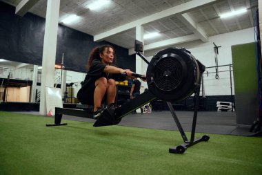Çapraz antrenman sırasında kürek çeken Afrikalı Amerikalı bir kadın. Spor salonunda yoğun bir şekilde egzersiz yapan bayan sporcu. Yüksek kalite fotoğraf