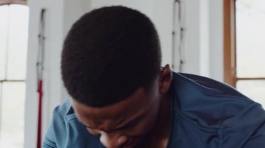 Determined and focused black male athlete cycling on stationary bike at indoor fitness gym. Camera slow full body shot. 