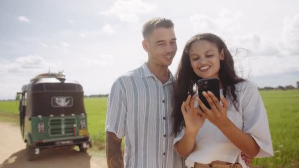 Happy Young Couple Smiling Scrolling Mobile Phone Rickshaw Dirt Road — Vídeo de stock