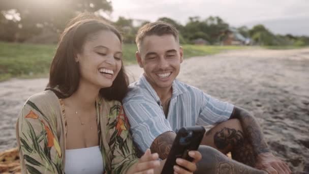 Happy Young Couple Sitting Beach Smiling While Scrolling Mobile Phone — Wideo stockowe