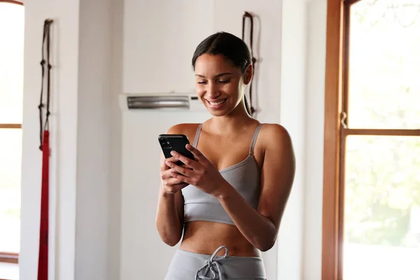 Mujer Biracial Joven Segura Ropa Deportiva Escribiendo Teléfono Móvil Gimnasio — Foto de Stock