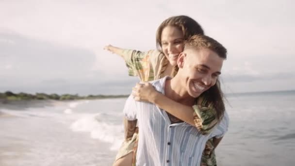 Happy Young Caucasian Man Carrying Girlfriend Back While Laughing Arms — Stock Video