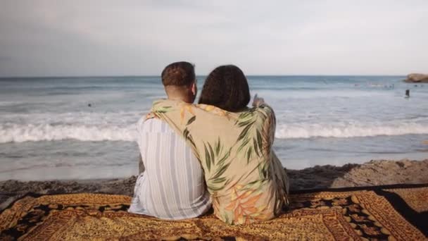 Visão Traseira Jovem Casal Afetuoso Apontando Para Mar Enquanto Sentado — Vídeo de Stock