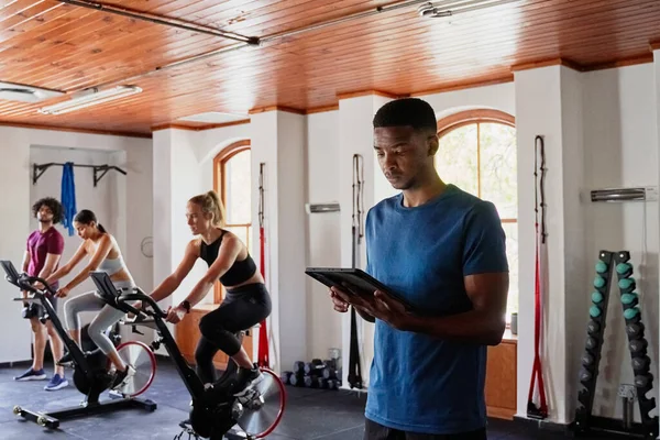 Professional young black man in sportswear using digital tablet at the gym